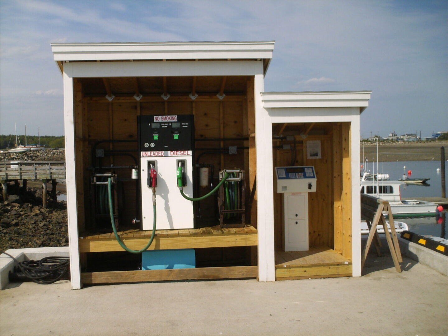 A small white building with two different types of gas pumps.