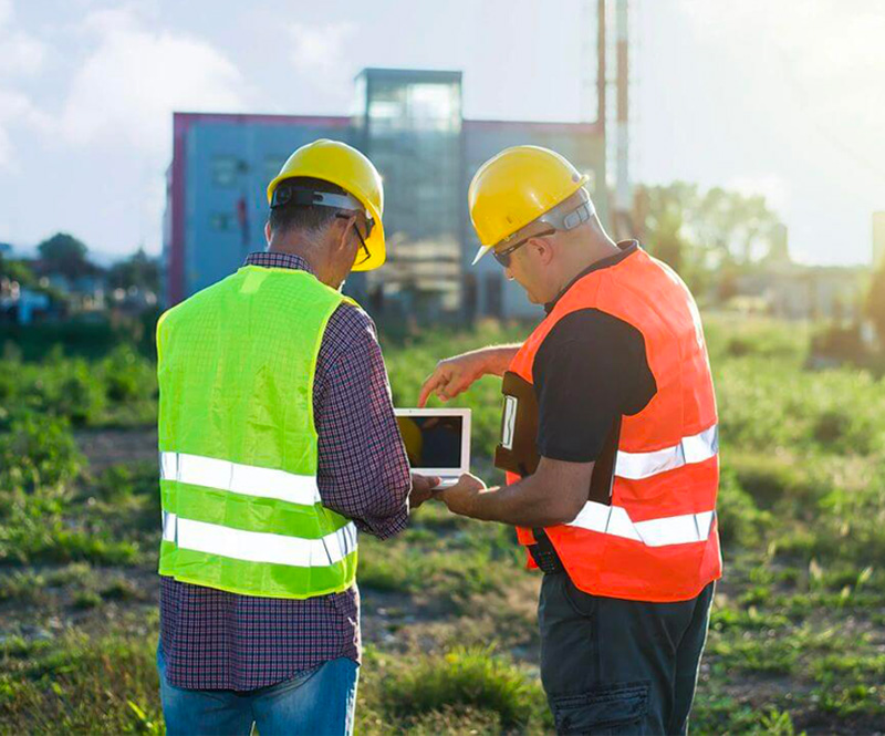 Construction workers reviewing plans on tablet.